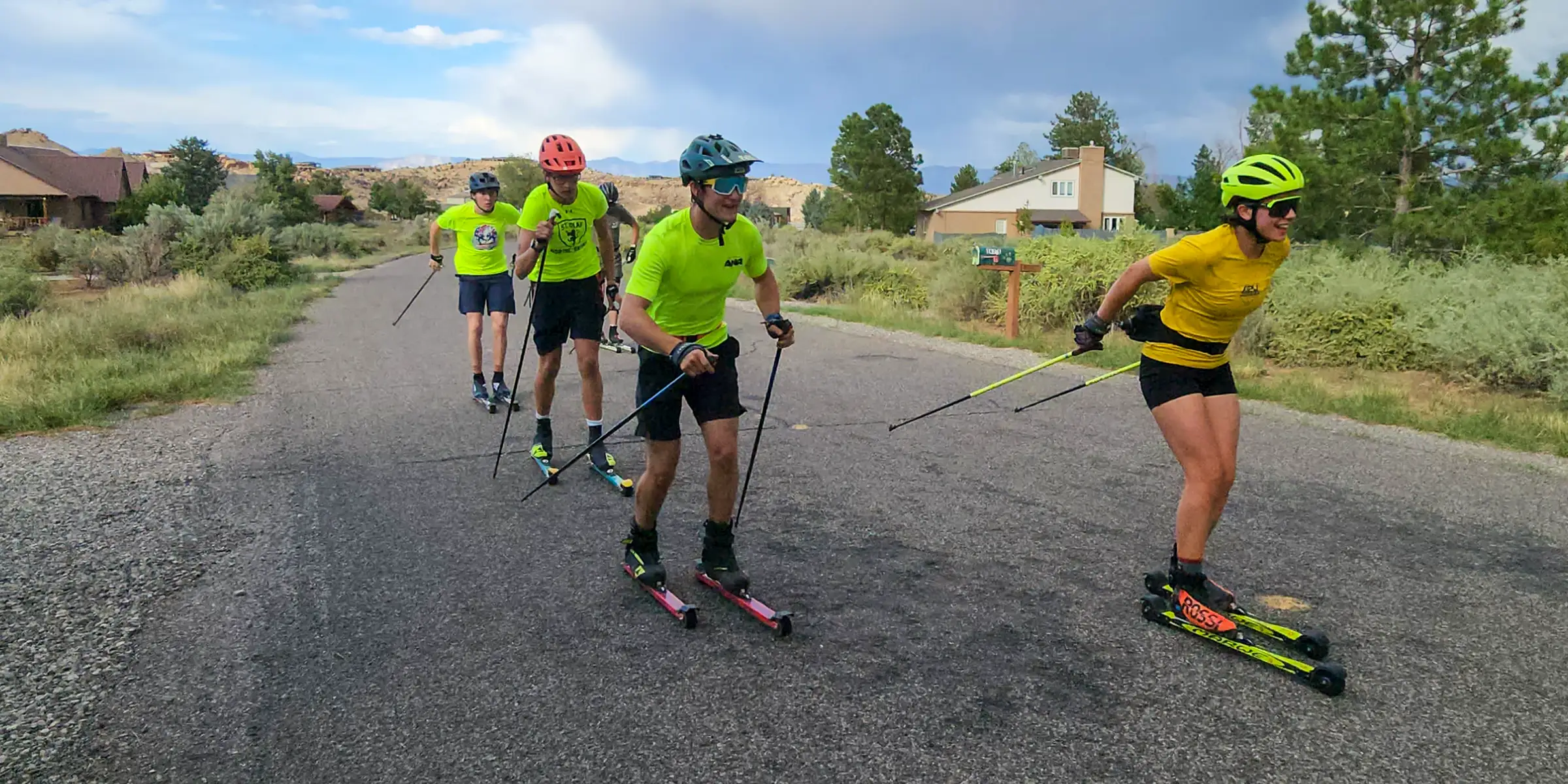 CMU Cross Country Ski Team athletes rollerskiing together on a mountain road