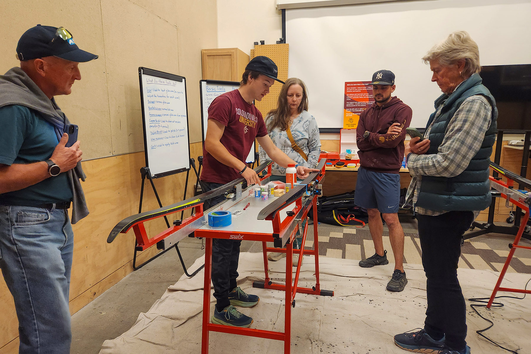 A Colorado Mesa University skier demonstrates grip waxing techniques on classic skis during the team’s free community clinic at REI Grand Junction, as attendees watch and ask questions.