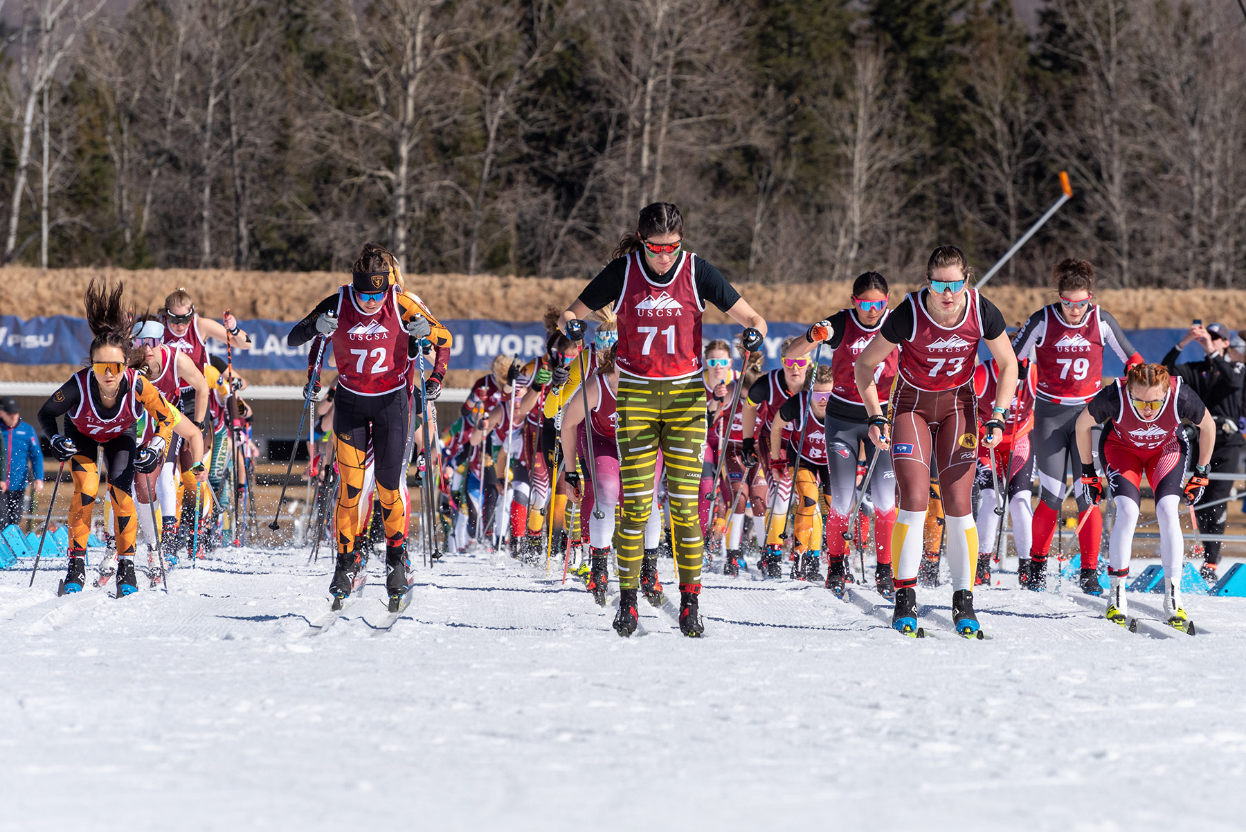 Women’s collegiate mass-start classic race, with athletes using a wide range of ski and pole lengths, demonstrating how equipment choices appear in actual competition.